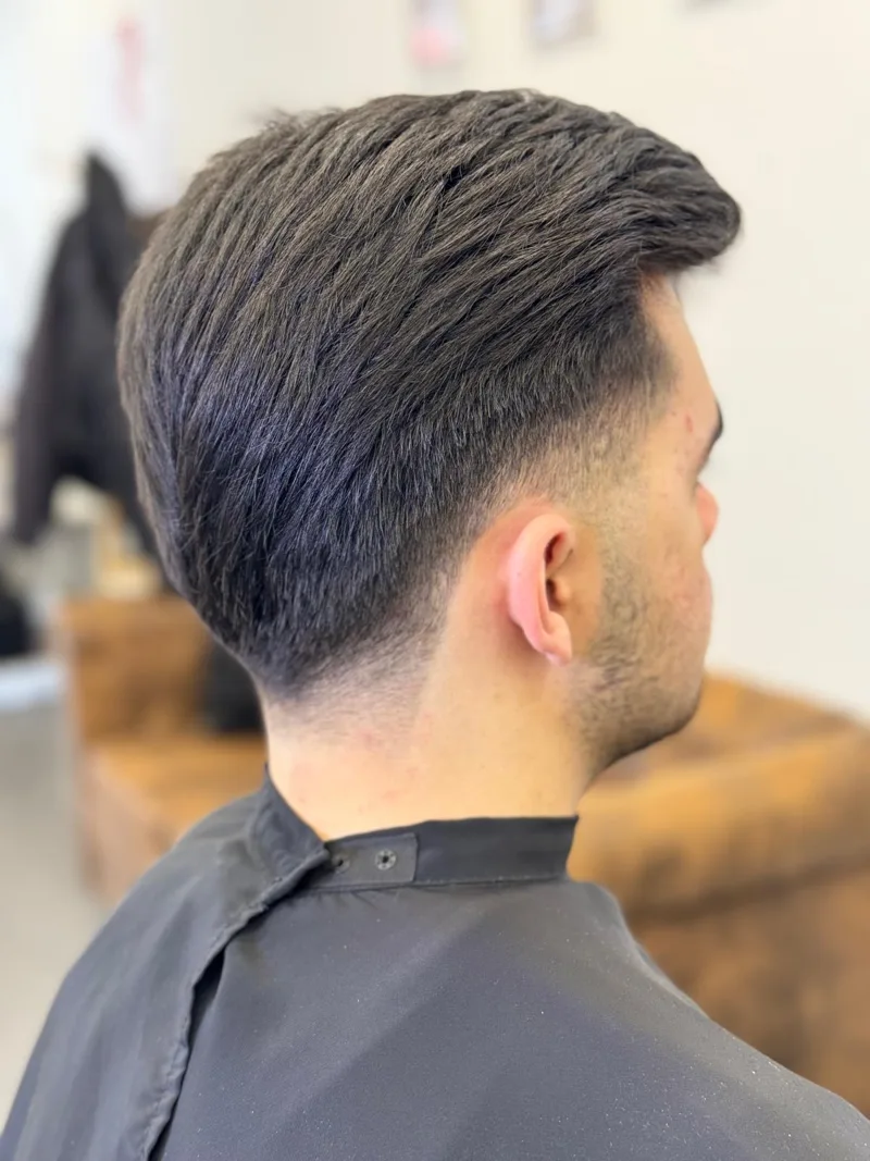 Corte de cabelo homem com degradado na nuca e volume no topo, vista traseira
